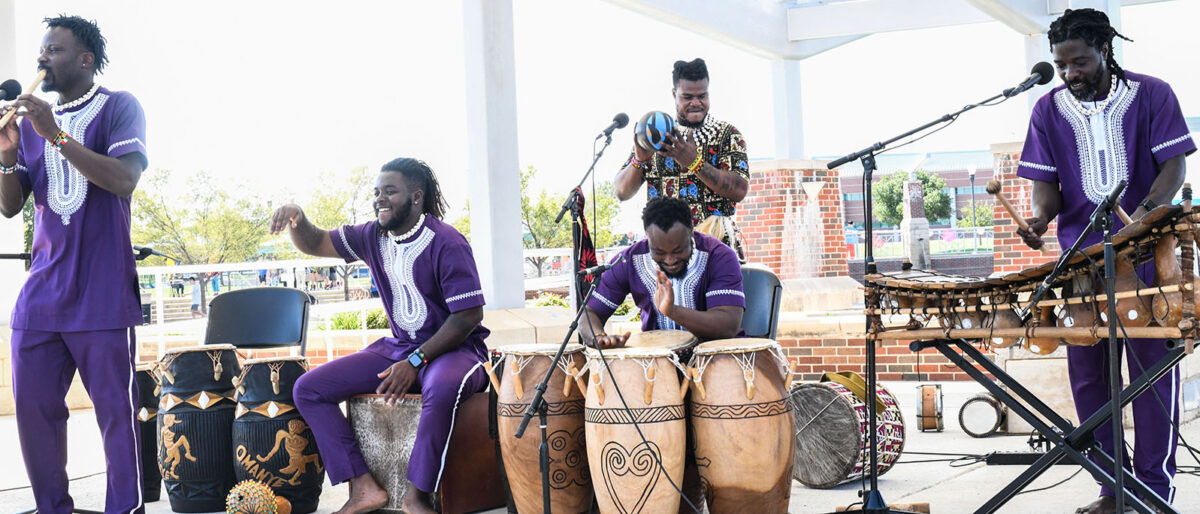 black men in purple clothes playing drums